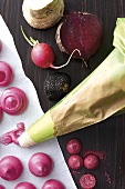 Pastry bag with fresh radishes, beetroot and macaroons on wooden platform
