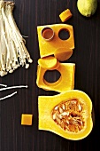 Cut out pumpkin with enoki mushrooms and lemon on brown surface