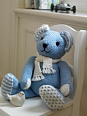 Close-up of blue knitted teddy on white chair
