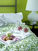 Breakfast on tray being served on bed with green and white linens