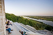 Tourists sitting on steps of Walhalla memorial overlooking the Danube river