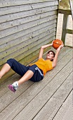 Young woman wearing sportswear exercising in supine position with basket ball
