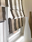 Close-up of brown and biege striped roman shades on window