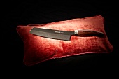 Close-up of chef's knife on red cushion