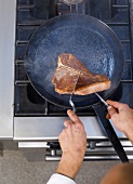 Turning the steak in frying pan, elevated view