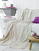 White wool blanket and purple scatter cushion on white leather couch