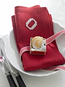 Pastry on red napkin with embroidered monogram on white plate