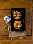 Stuffed onions in a baking dish with dip in bowl, overhead view