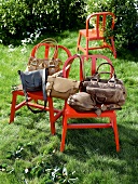 Various hand bags on red chairs in lawn