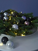 Baubles on fir branches with light decorations on plate for Christmas