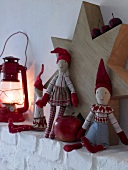Mantelpiece decorated with Christmas elf dolls, lantern and star shaped wood