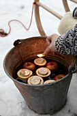 Lit candles in hollowed out apple halves bucket of water