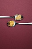 Bautz'ner mustard in teaspoons on maroon background