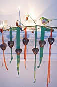 Candy hearts on ribbons hanging from rosehip branch on mantel