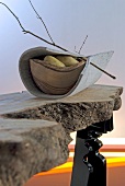 Close-up of bowl with potatoes wrapped in felt and twig on rustic wooden table