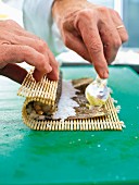 Sushi being made: wasabi being spread on a nori sheet
