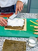 Putting cooked rice on nori sheet for preparing tuna sushi