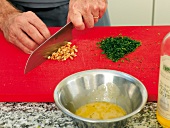 Chopping pine nuts on cutting board for pine nut vinaigrette