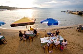 Elevated view of people dinning on beach at sunset