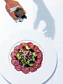 Beef carpaccio with salad and winter truffle on plate, overhead view
