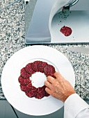 Man's hand arranging beef slices on dish