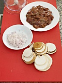 Two plates of duck liver and rice with sliced mushrooms on red board