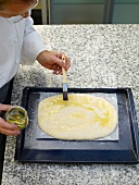Man applying oil to focaccia bread with oil brush