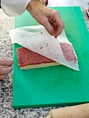 Paper being removed from coated focaccia bread tatar on green board