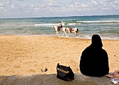 Woman watching man riding horse on beach during summer vacation at Kilyos, Turkey