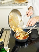 Man's hands adding shrimps to tomato sauce in pan