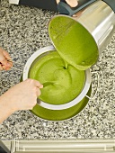 Green puree being strained with strainer