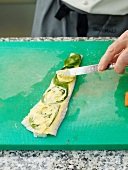 Close-up of man's hands applying sauce with knife on leaves on sole fish
