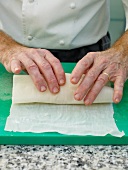 Close-up of man's hands wrapping sole with baking paper