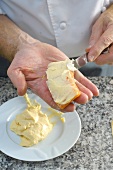 Close-up of man's hands applying dough to salmon fillet with knife