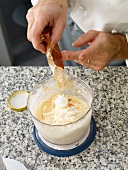 Spice being added to mixture of minced fish and cream while preparing fish farce