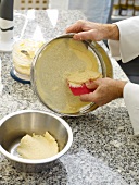 Mixture of minced fish and cream being removed from strainer