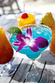 Close-up of blue cocktail with purple flower in glass