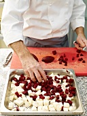 Chef placing diced beetroot in baking tray for preparing beetroot puree