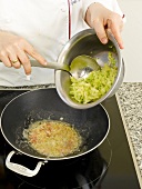 Sliced cabbage being mixed with paste in cooking pan