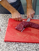 Venison being sliced on cutting board