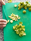 Brussels sprouts being sliced on cutting board