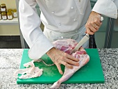 Chef slicing lamb's leg on board