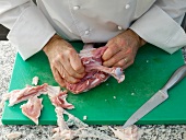 Chef cutting lamb's leg with knife