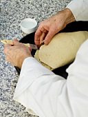 Chef sealing salt dough with stuffed lamb's leg