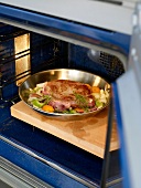 Beef steak and vegetables placed in oven