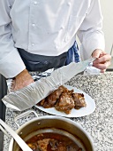 Aluminium foil being wrapped over veal cheeks on serving dish