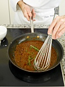 Mixing partially cooked sauce with whisk in frying pan