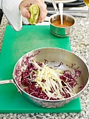 Squeezing lemon on red cabbage and apple in saucepan
