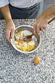Mixing shredded potato with egg in bowl for potato dumplings