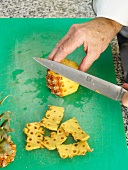 Slicing pineapples on chopping board